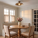 A farmhouse dining nook featuring the Titan Semi-Flush Mount in patina brass installed over a round wood table with a built-in banquette and white shiplap walls.