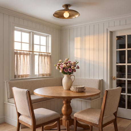 A farmhouse dining nook featuring the Titan Semi-Flush Mount in patina brass installed over a round wood table with a built-in banquette and white shiplap walls.