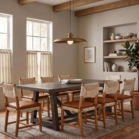 A transitional dining room with the Titan Extra Large Pendant 32 in patina brass over a dark wood table with woven chairs and exposed ceiling beams.