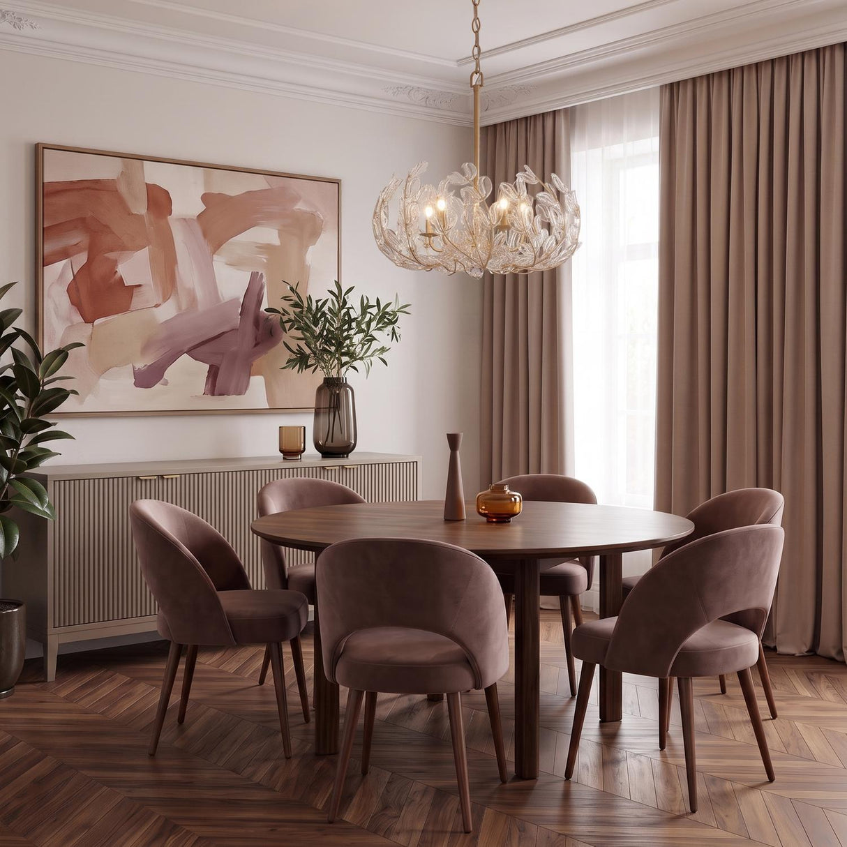 A contemporary dining room featuring the Esme Chandelier in soft brass and clear glass suspended over a round walnut table with mauve velvet chairs and herringbone floors.