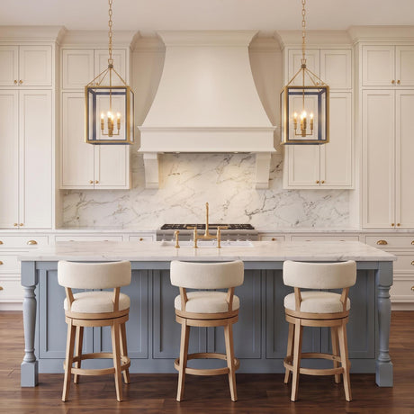 A transitional kitchen featuring two Ramona Medium Lantern Pendants in brushed brass and vintage blue over a marble island with a blue base and cream stools.
