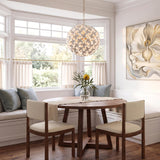 A transitional dining room featuring the white ceramic Nabi Pendant 22", Brass and White over a round walnut table and built-in bench seating with blue pillows.