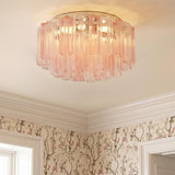 A traditional bedroom featuring the Grace Flush Mount 22", Chrome with Blush Glass installed along the ceiling center above floral wallpaper and white crown molding.