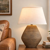 A transitional living room features the Welles Table Lamp 22", Fluted Brown with White Shade on a wooden side table next to a brown leather sofa.