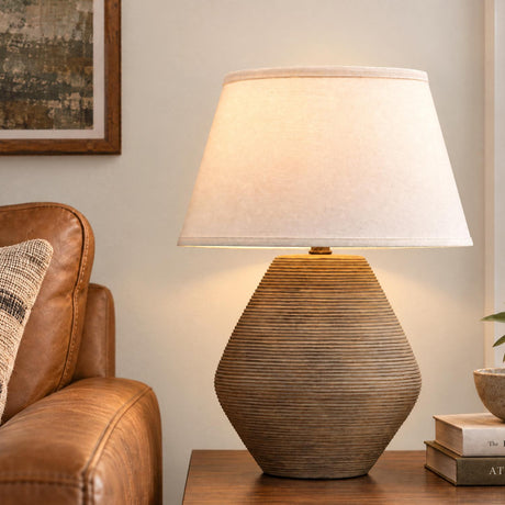 A transitional living room features the Welles Table Lamp 22", Fluted Brown with White Shade on a wooden side table next to a brown leather sofa.