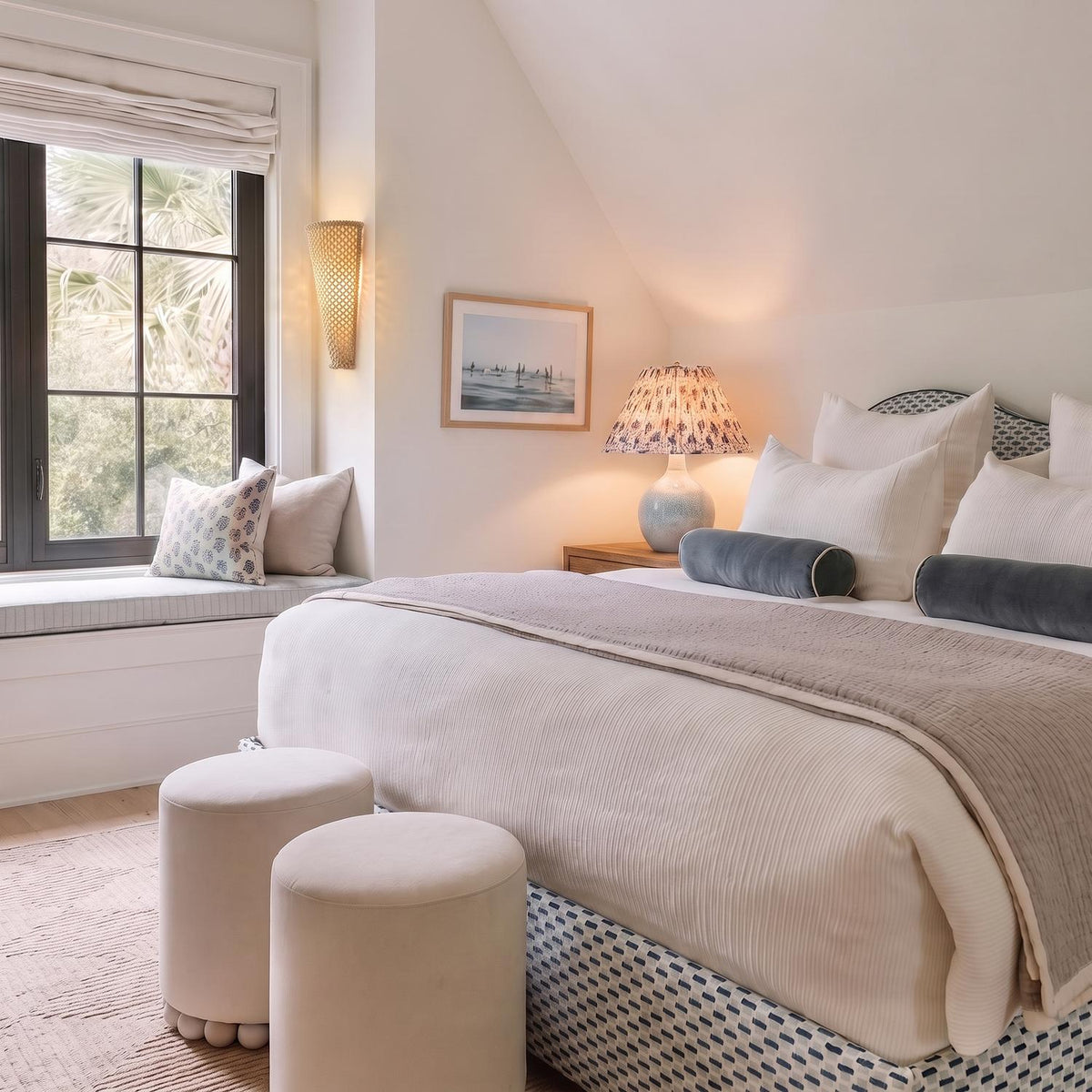 A coastal bedroom features the Jessa Table Lamp 27", Light Blue Glaze with Slate Bloom Printed Shade on a wooden nightstand under a sloped ceiling.