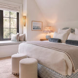 A coastal bedroom features the Jessa Table Lamp 27", Light Blue Glaze with Slate Bloom Printed Shade on a wooden nightstand under a sloped ceiling.