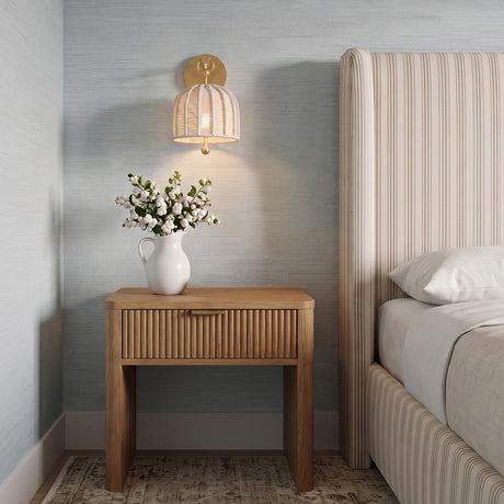 A coastal bedroom featuring the Benito Wall Sconce 12 inch in gold leaf and natural rope mounted above a fluted wood nightstand and striped headboard.