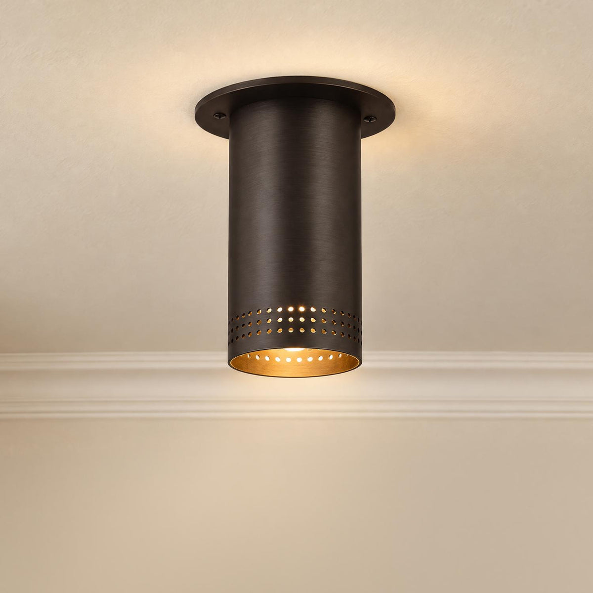 A mid-century foyer featuring the Bevan Small Cylinder Flush Mount 5", Bronze with perforated detailing and a gold interior mounted on a beige ceiling near crown molding.