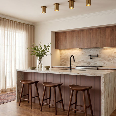 A transitional kitchen with four patina brass Bevan Small Cylinder Flush Mounts along the ceiling over a marble waterfall island and walnut upper cabinets.
