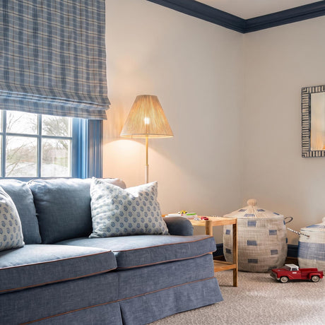 A cottage living room features the Birdie Floor Lamp 64", Gold Leaf and Natural Rope, beside a blue denim sofa with navy blue crown molding.