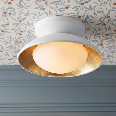 A transitional foyer with a white and gold leaf flush mount featuring a frosted glass globe on a blue floral wallpapered ceiling above blue wall paneling.