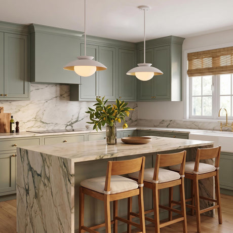 A transitional kitchen features two Vera Medium Pendants in white and gold leaf hanging over a marble waterfall island surrounded by sage green cabinets.