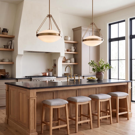 A transitional kitchen with two Dunmore Large Pendants in patina brass over a natural wood island with black countertops, open wood shelving, and a plaster range hood.