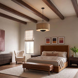 A mid-century bedroom with the Linwood Oversized Pendant 38", Forged Iron and Raffia drum pendant suspended from a beamed ceiling over a cognac leather bed.