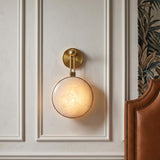 A transitional bedroom with a vintage brass and onyx Heloise LED wall sconce 17" mounted on a white paneled wall beside a studded leather headboard.