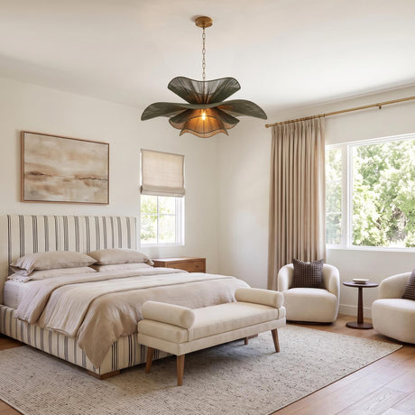 A transitional bedroom with the Lotus Chandelier 44", Patina Brass and Rosemary Cotton hanging from a standard ceiling over a striped upholstered bed and cream bouclé chairs.