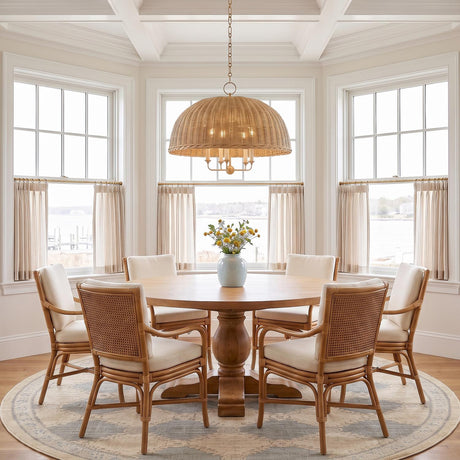 A coastal dining room featuring the Valencia 5 Light Pendant 30", Aged Brass and Natural Wicker suspended over a round wooden table beneath a coffered ceiling.