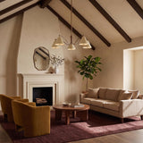 A transitional living room with the Bryden 5 Light Chandelier in patina brass and soft sand centered along a beamed vaulted ceiling above a round wood coffee table.