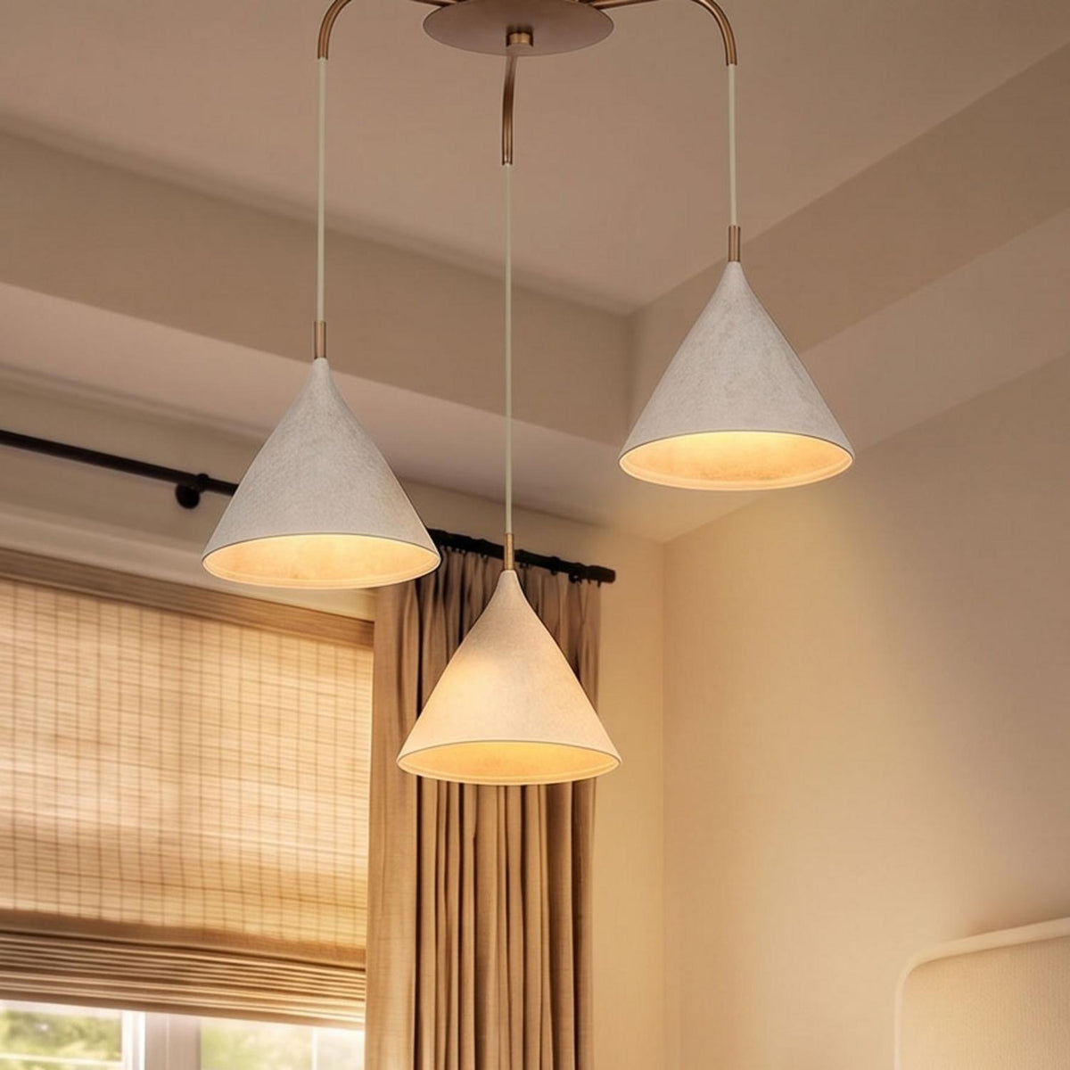 A transitional bedroom with the Harlen 3 Light Chandelier, Patina Brass and Limewash suspended from the ceiling beside beige drapes and woven shades.