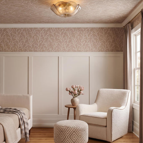 A transitional bedroom with the Fiorenzo Flush Mount in aged brass and smoke taupe glass along the ceiling above cream paneling and branch-patterned wallpaper.