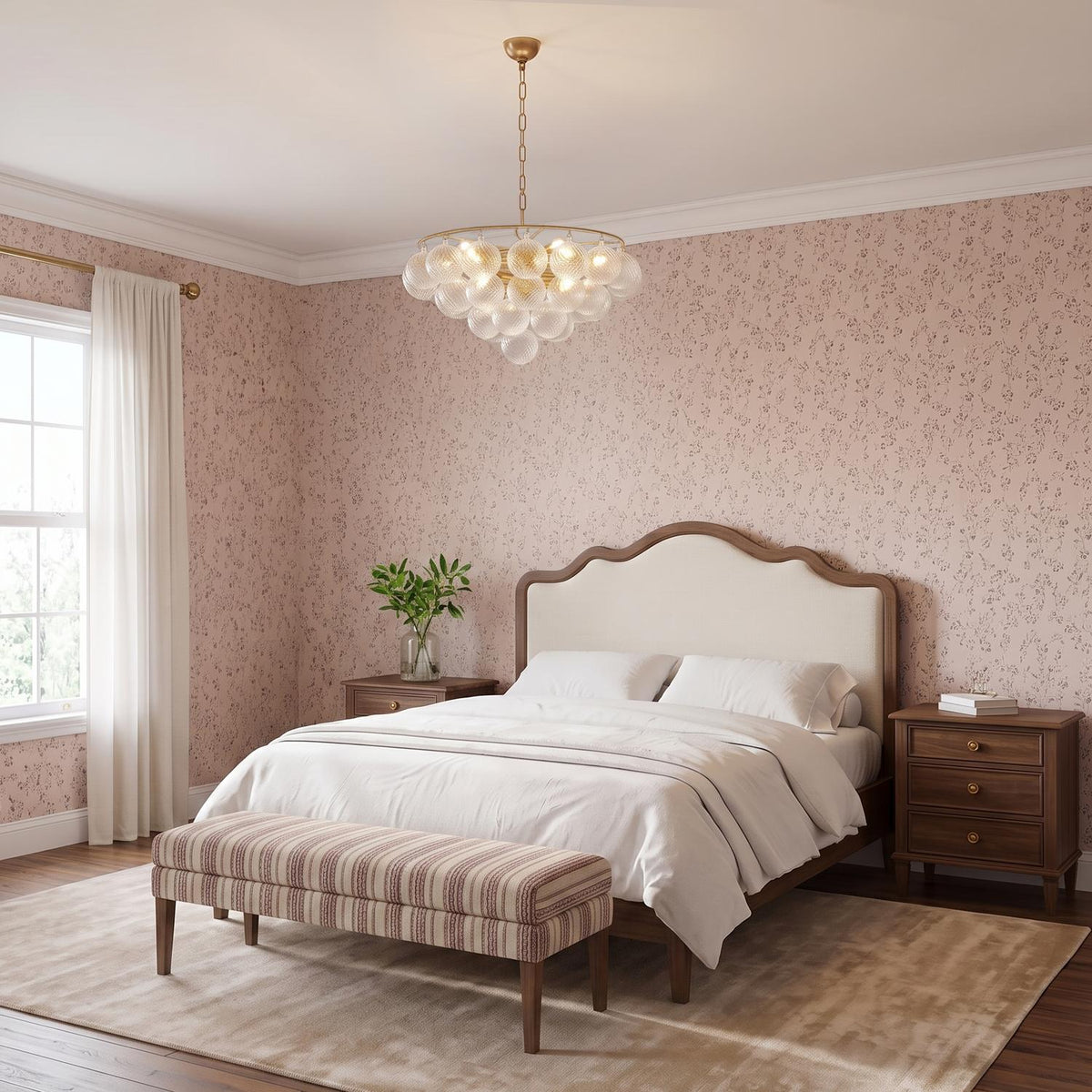 A traditional bedroom featuring the Kassia 9 Light Chandelier in aged brass and swirled glass over a wood-framed bed with pink floral wallpaper and white curtains.