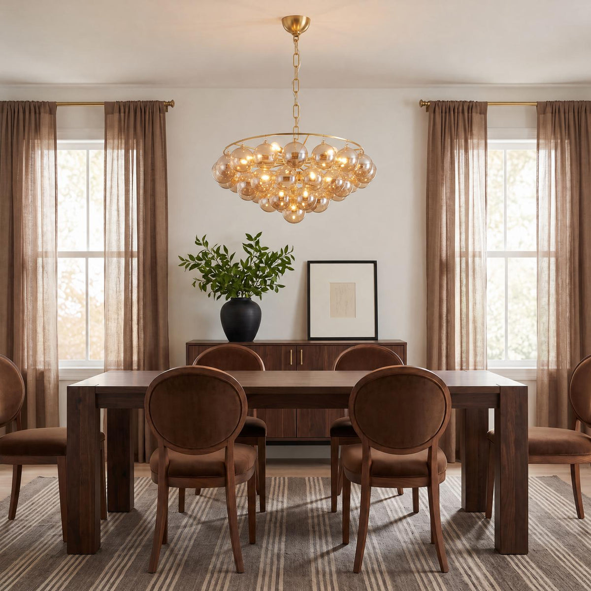 A contemporary dining room features an aged brass chandelier with mirrored champagne glass globes suspended over a dark wood table surrounded by oval-back chairs.