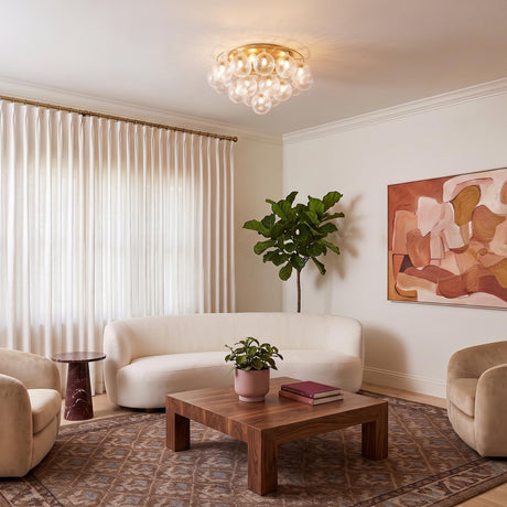 A contemporary living room with the Kassia 6 Light Semi-Flush in aged brass and clear swirled glass centered above a curved white sofa and walnut coffee table.