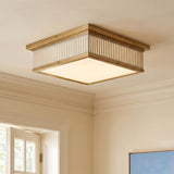 A transitional foyer with a Hawthorne Square LED Flush Mount in aged brass and off-white glass along the ceiling above classic crown molding and a white door.