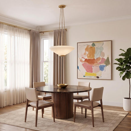 A contemporary dining room with the Lindor Large Pendant 22 in aged brass and opal glass hanging over a dark wood circular table with beige chairs.