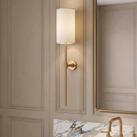 A transitional bathroom with an aged brass Riven Rechargeable Wall Sconce 19" featuring a white linen shade mounted on taupe paneled walls beside a marble vanity.