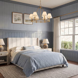 A transitional bedroom featuring the Rafferty 6 Light Chandelier 33", Aged Brass with white fabric shades over a striped upholstered bed and blue wainscoting.