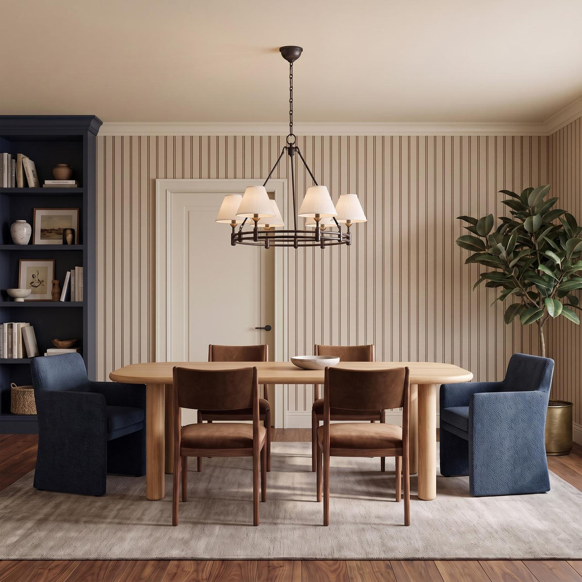 A transitional dining room with a distressed bronze and aged brass chandelier featuring linen shades over a light wood table and navy blue built-in shelving.