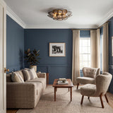 A transitional living room featuring the Perenna Semi-Flush in patina brass and smoke taupe glass above blue paneled walls, beige boucle armchairs, and a walnut coffee table.