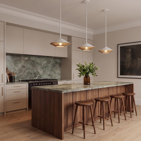 A contemporary kitchen featuring three Sunita Medium Pendants in matte white and rope hanging over a walnut island with green marble countertops and wooden barstools.