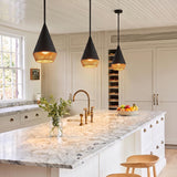 A modern farmhouse kitchen featuring three Sunita Small Pendants in matte black and rope over a white marble island with a brass faucet and beadboard ceiling.