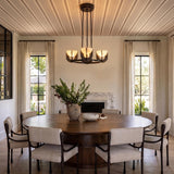 A transitional dining room featuring the Armand LED Chandelier with an urban bronze finish and alabaster shades over a round walnut table and marble fireplace.