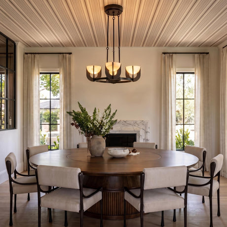 A transitional dining room featuring the Armand LED Chandelier with an urban bronze finish and alabaster shades over a round walnut table and marble fireplace.