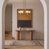 A transitional foyer features an Armand LED Chandelier 28", Vintage Brass and Alabaster suspended above a light wood console table and patterned runner framed by an archway.