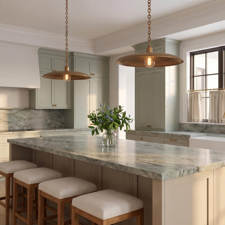 A transitional kitchen with two Crawford Large Pendant 19", Patina Brass pendants hanging over a gray marble island with sage green cabinetry and upholstered wooden stools.