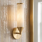 A contemporary bathroom featuring a Sayer Wall Sconce in aged brass and cloud glass mounted on a cream ceramic tile wall beside a gold framed mirror.