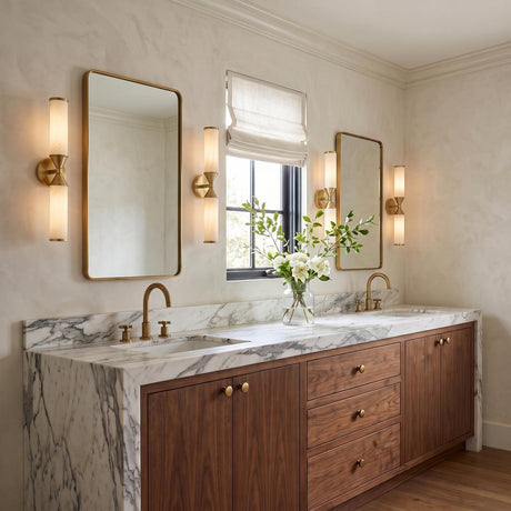 A transitional bathroom with aged brass and cloud glass wall sconces flanking two rectangular mirrors above a white marble double vanity featuring walnut wood cabinets.