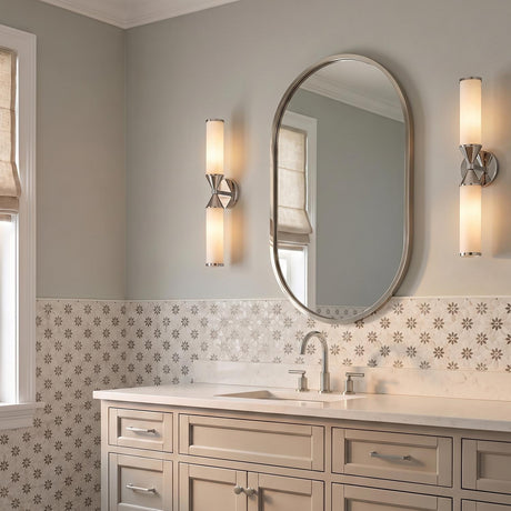 A transitional bathroom with two polished nickel and cloud glass wall sconces flanking an oval mirror above a white quartz vanity and floral patterned tile.