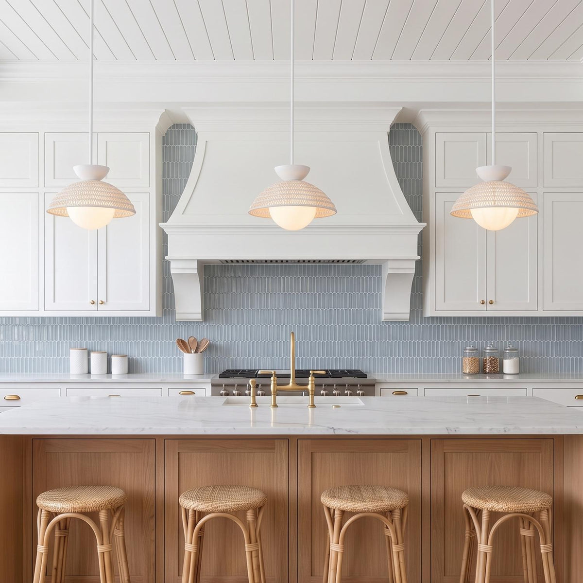A coastal kitchen featuring three Santino Pendant Matte White and White Rattan fixtures over a marble island with light wood cabinets and blue picket tile backsplash.