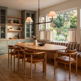 A transitional dining room with the Casimir 2 Shade Linear Pendant 61", Aged Iron and linen shades suspended over an oval wood table and sage green cabinetry.