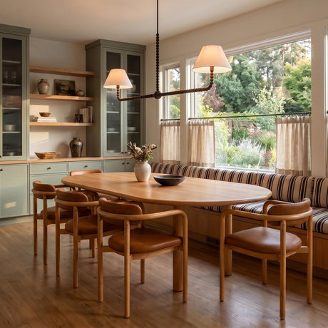 A transitional dining room with the Casimir 2 Shade Linear Pendant 61", Aged Iron and linen shades suspended over an oval wood table and sage green cabinetry.