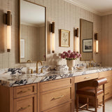 A transitional bathroom featuring four Anders Large LED Wall Sconces in weathered brass and alabaster flanking mirrors over a veined marble vanity and wood cabinets.