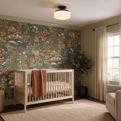 A transitional nursery with a light wood crib features the Lavinia Semi-Flush 11", Aged Iron and Opal Glass light mounted on the ceiling against colorful botanical wallpaper.