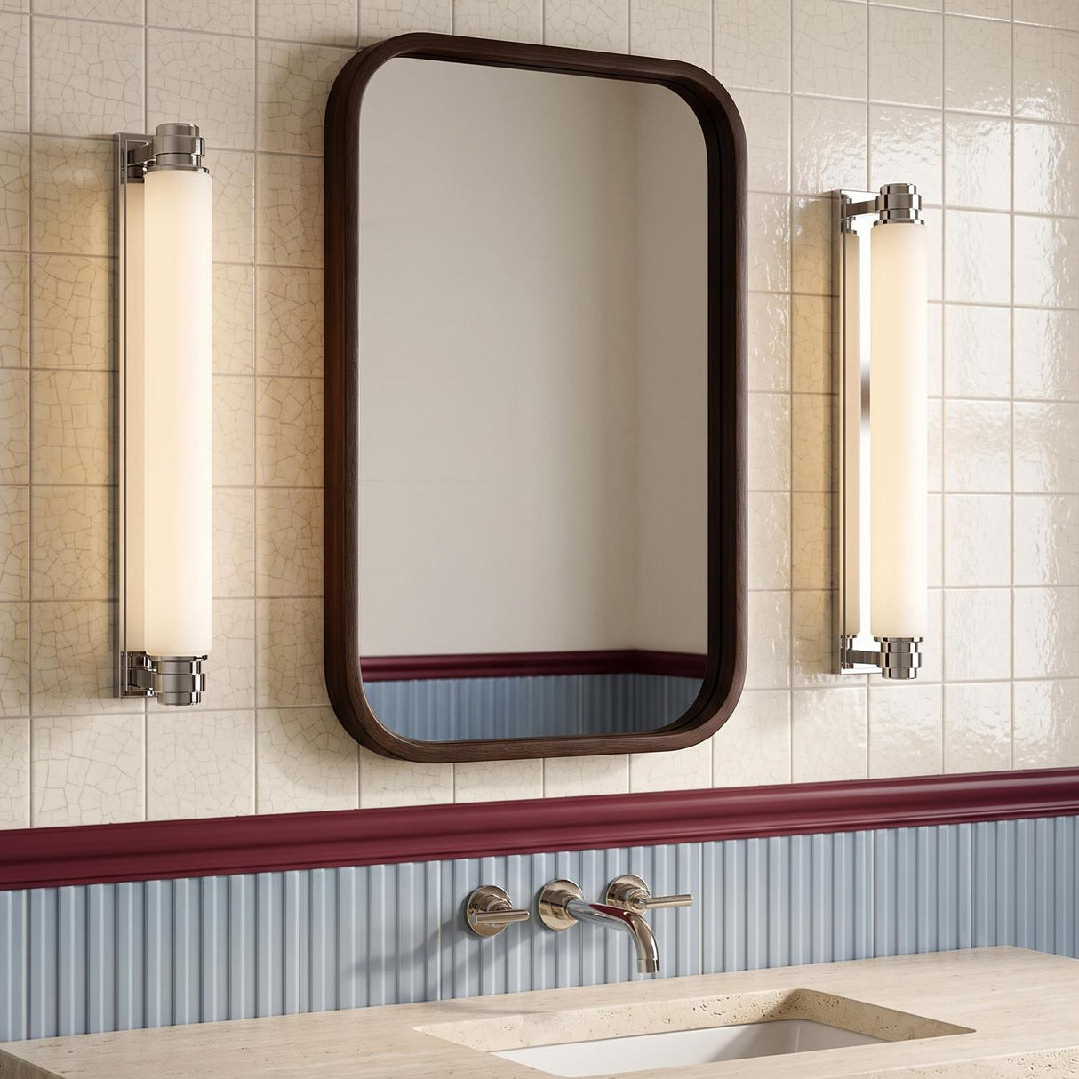 A transitional bathroom featuring two Lavinia LED Wall Sconces in polished nickel and opal glass flanking a wood-framed mirror over a beige stone countertop.