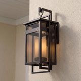 A modern home entry with the dark bronze Lansing Outdoor Wall Light and brown smoke glass glowing on a stucco wall at dusk under a white ceiling.
